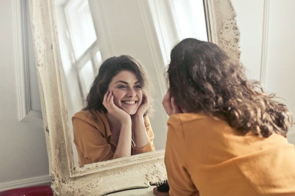 женщина смотрит в зеркало и улыбается